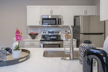 kitchen with stainless appliances and white cabinetry at Saw Mill Village apartments
